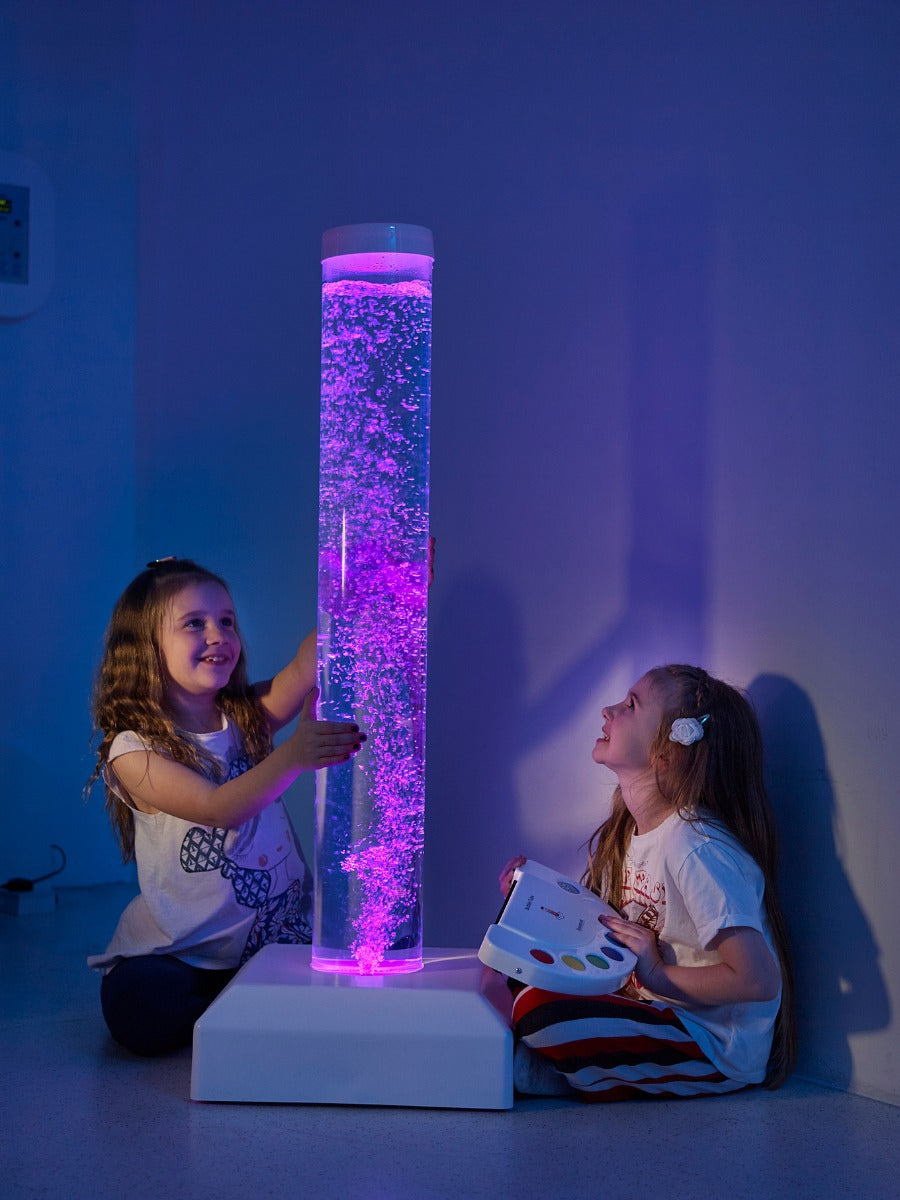Two children watch the colourful bubbles rise in a tall bubble tube